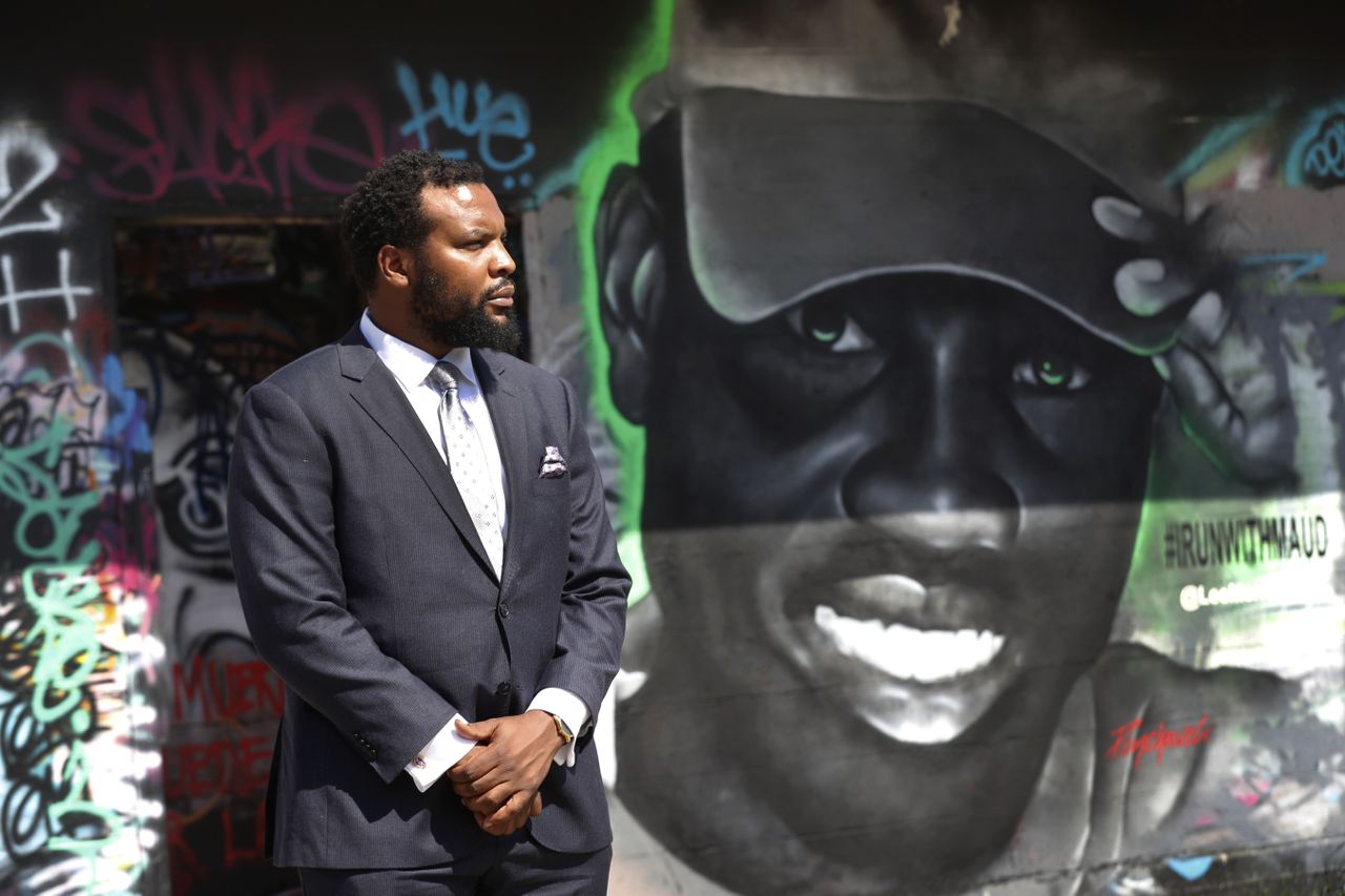 An attorney for the Arbery family stands next to a mural of Ahmaud Arbery.