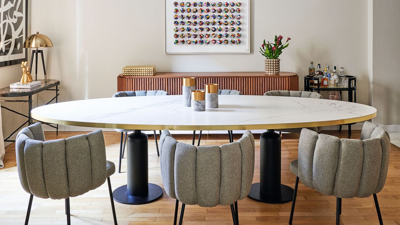 Neutral toned dining room colour scheme with grey chairs, white table and art hanging on wall