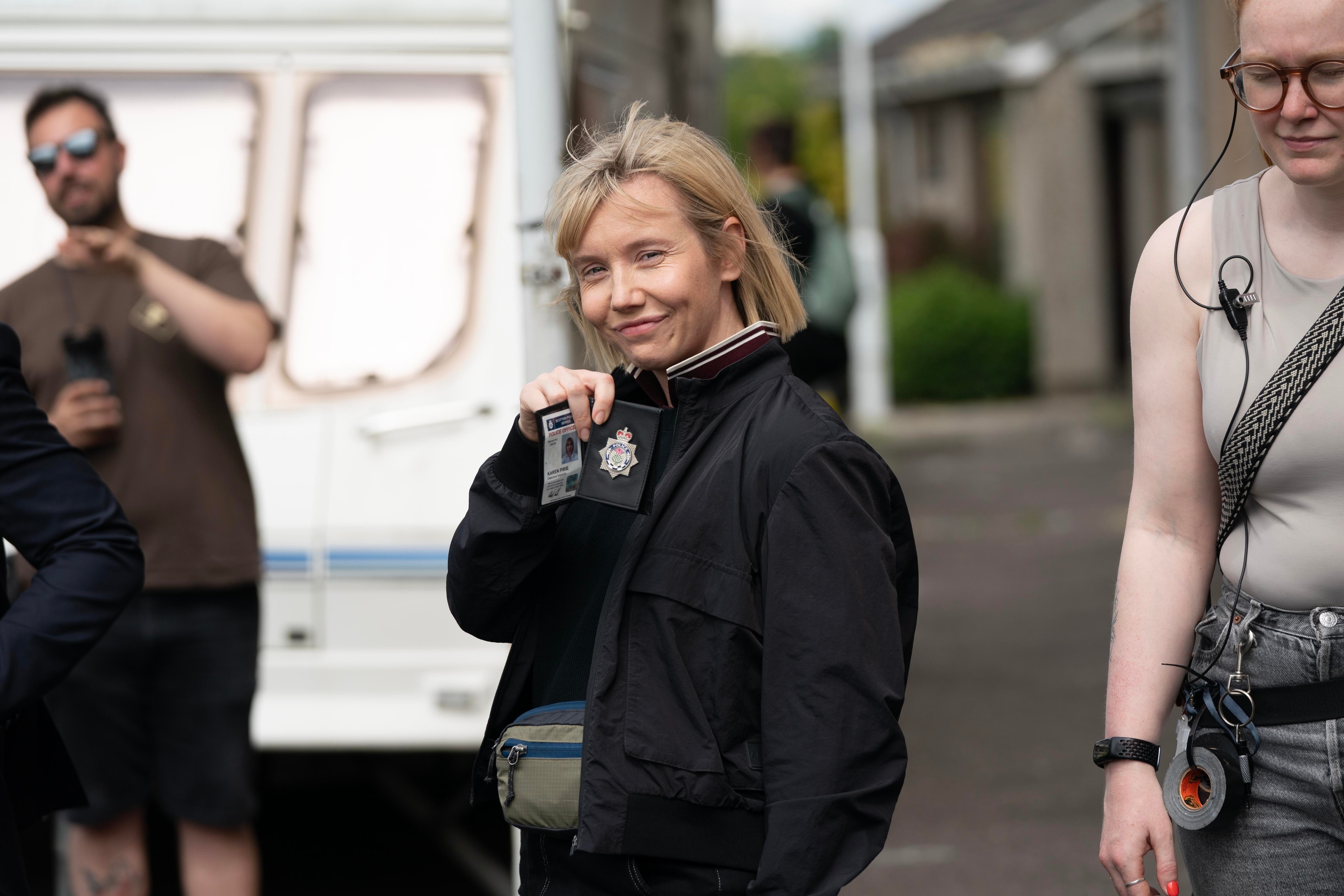 Lauren Lyle on set as Karen Pirie holding up her police ID card.