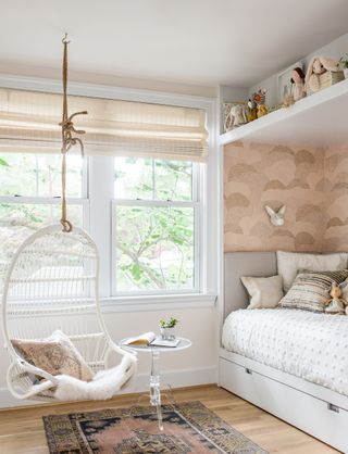 neutral kids room with hanging swing, wallpaper, rug, toy shelf, day bed