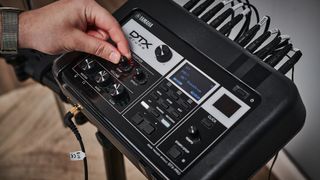 Closeup of the Yamaha DTXPRO module with someone turning the 'comp' dial