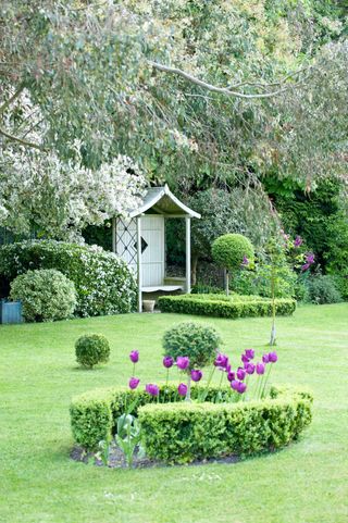 garden arbor ideas: green bench with roof in country garden