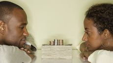 A husband and wife contemplate a stack of money between them.