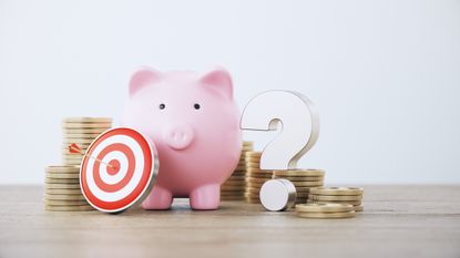 a piggy bank next to a question mark with a stack of coins behind it