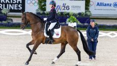 Nicola Naylor rides her horse Humberto L down the centre line at the World Para Dressage Championships in Aachen, while just to one side of her, her caller Julie Riches stands unmounted beside her