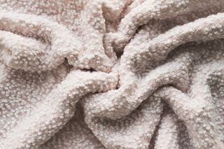 A close up image of a fluffy cream blanket texture.