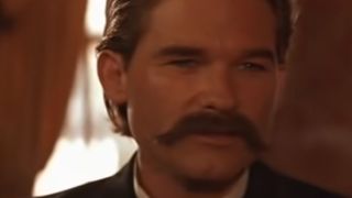 Kurt Russell with a mustache looking past the camera in Tombstone