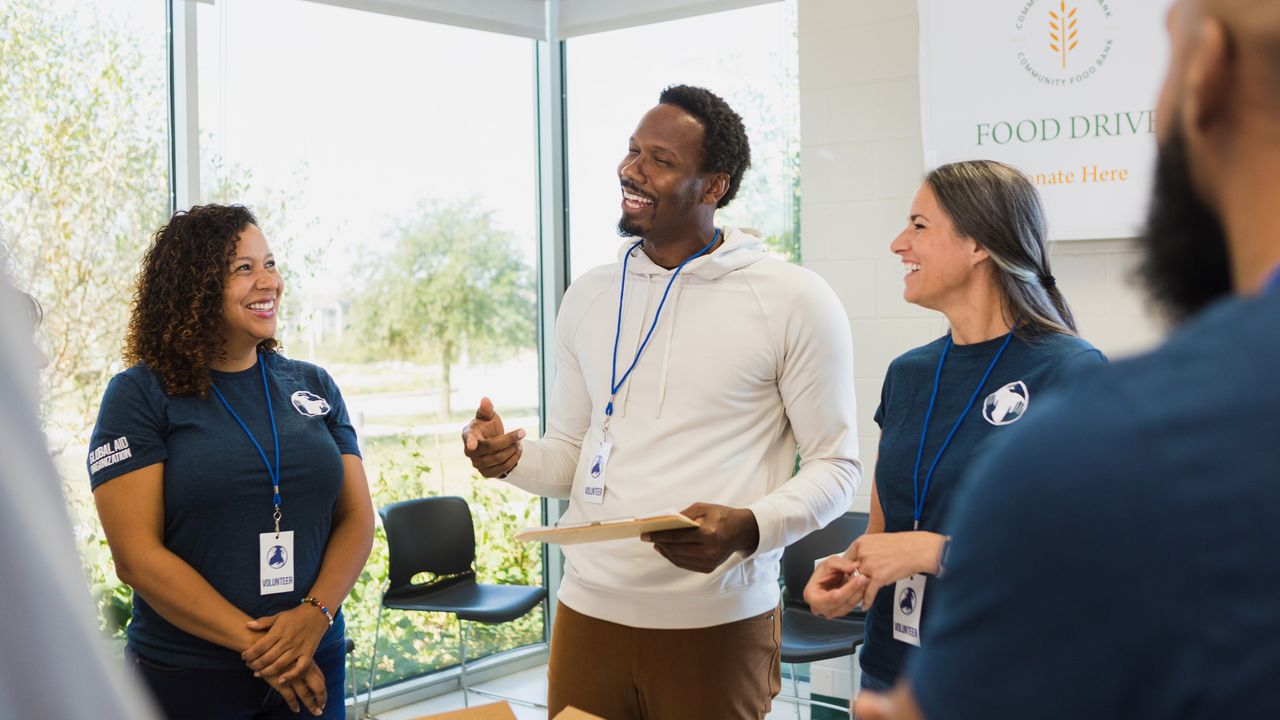 A man in charge of a nonprofit stands in an office with two women who are volunteers.