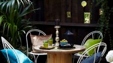 Black painted fence with dining set and green plants