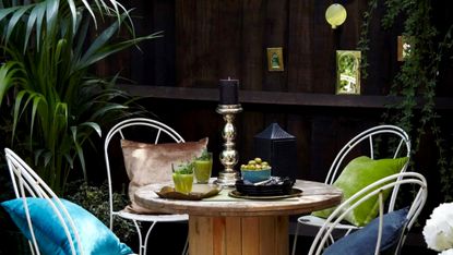 Black painted fence with dining set and green plants