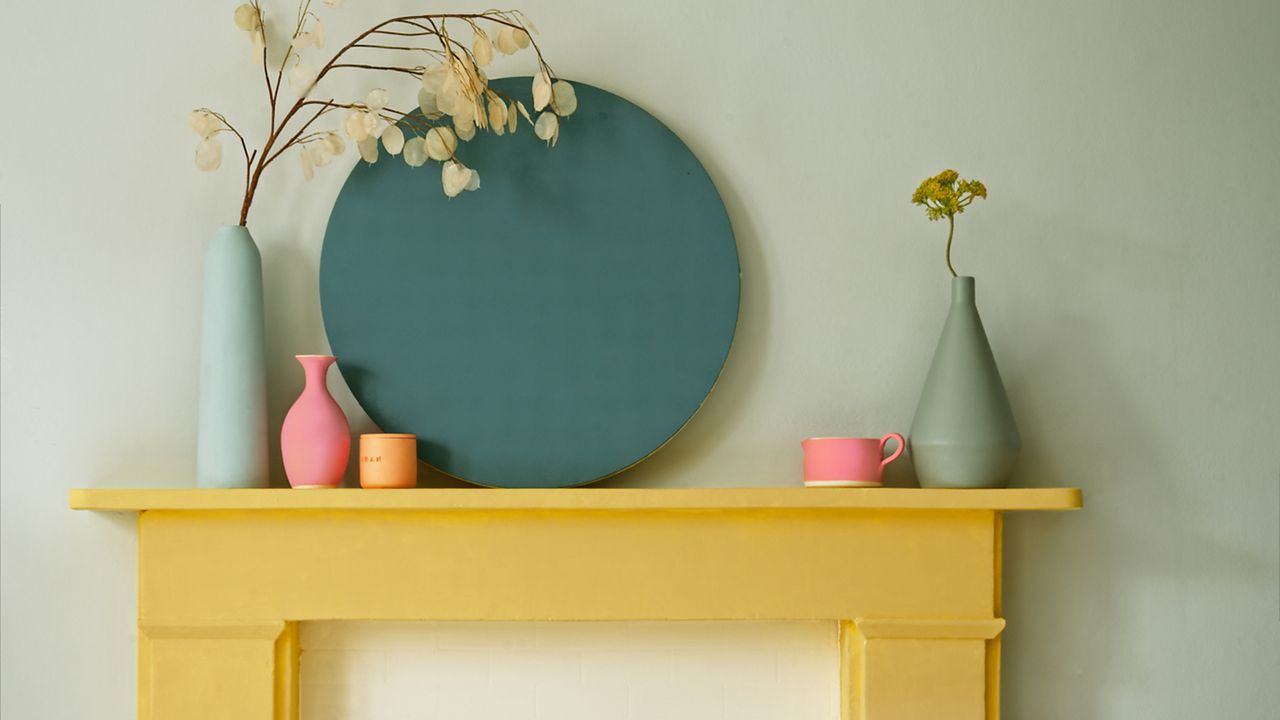 Yellow painted fireplace with painted vases against a white wall