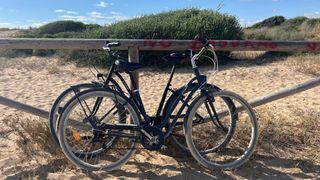 Two B'Twin bikes leant on a beachside fence