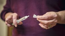 A woman's hands take the cap off a semaglutide pen