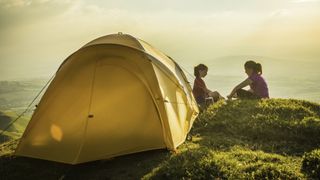 Two children beside a tent pitched on a hill