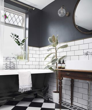 A monochrome black and white bathroom with checkerboard-style floor tiles and bathroom window with stained glass decor detail