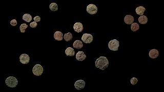 A cache of 26 coins found in Wales against a black background.