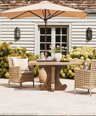 neutral colored paving on a patio with a table, chairs and patio umbrella