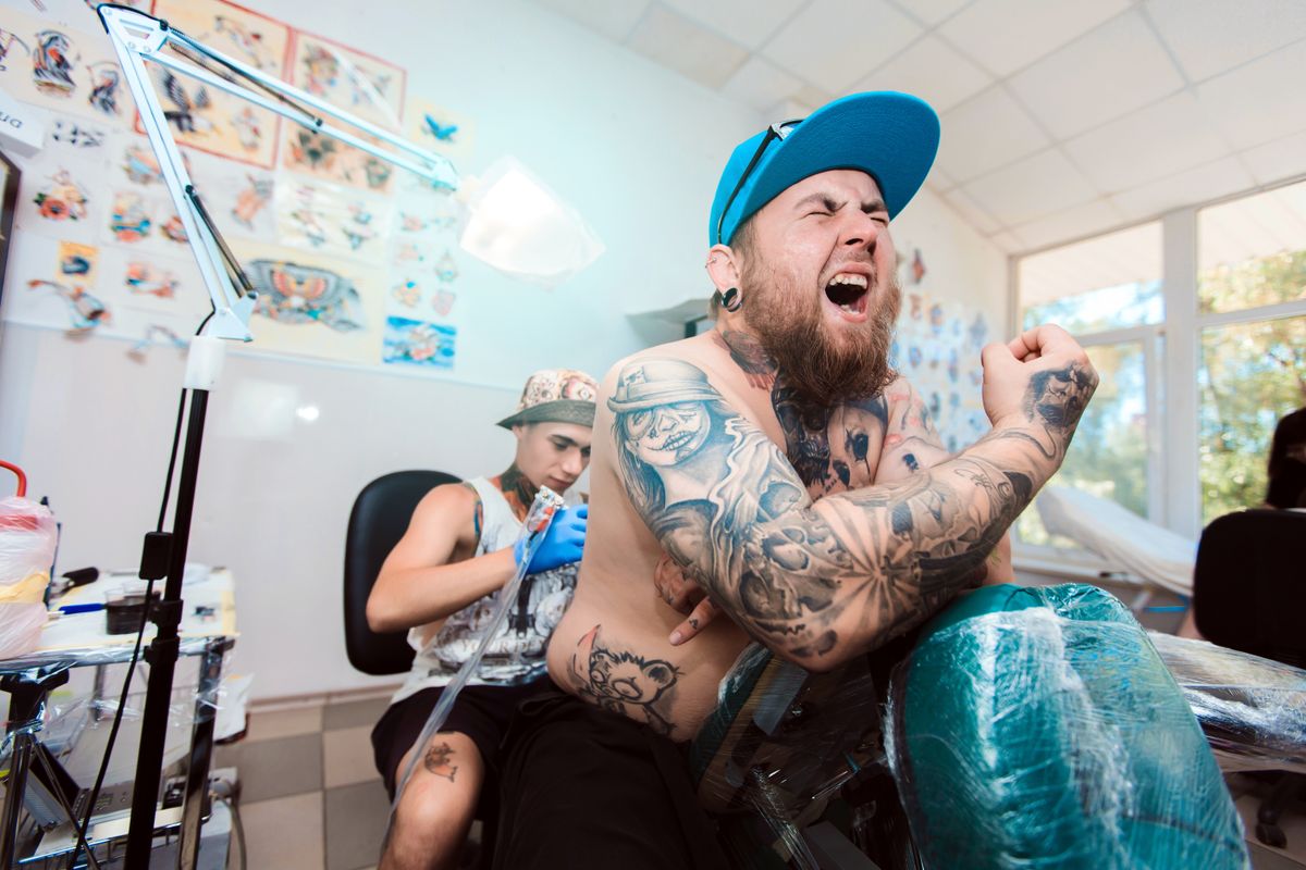 Man in pain at tattoo shop