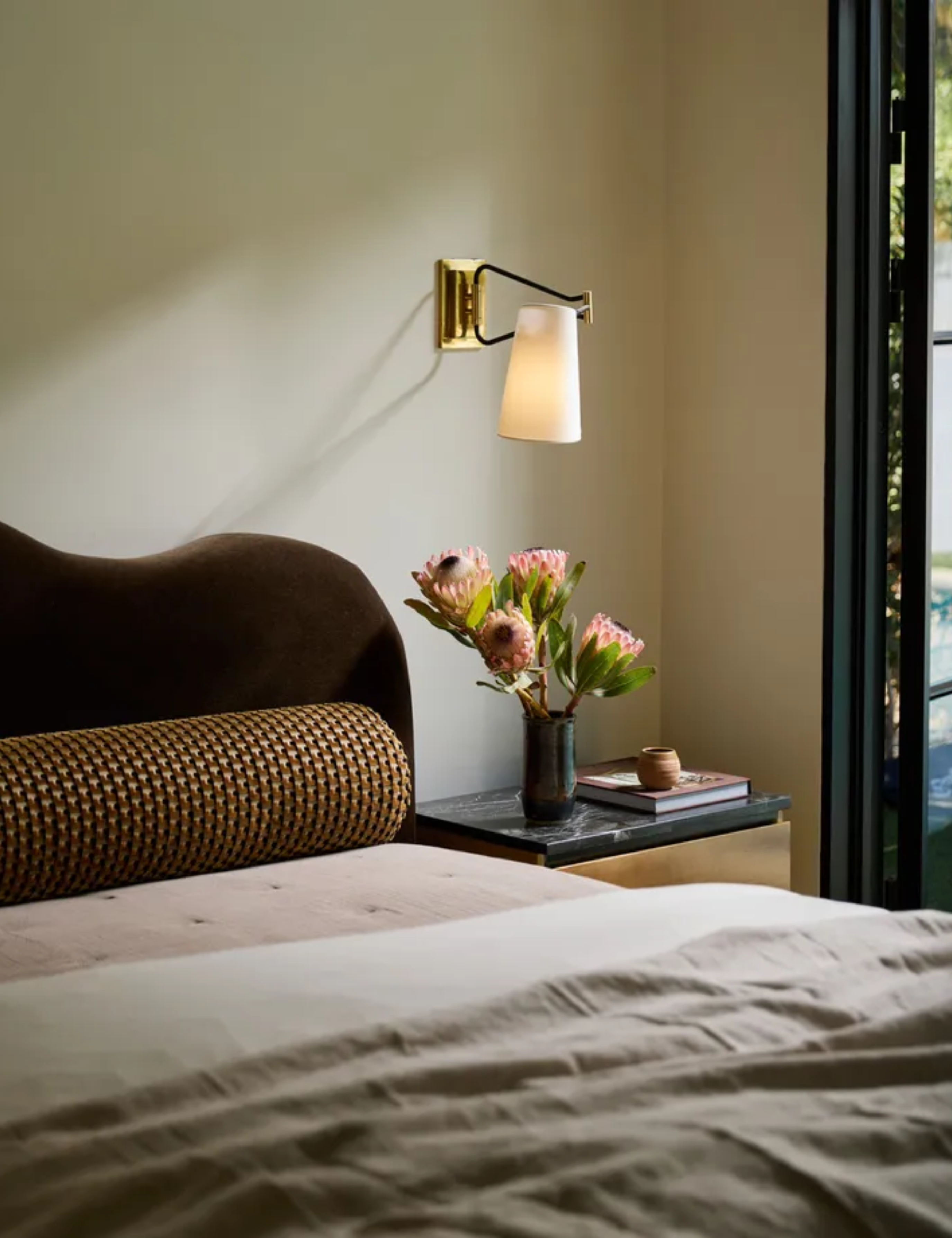 bedroom with scalloped headboard and gold wall light