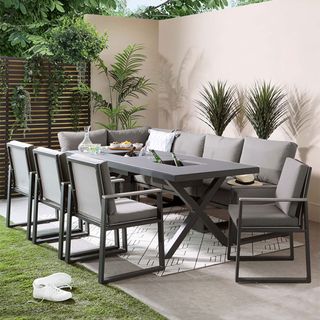 garden area with grey chairs and table and corner bench with cushions