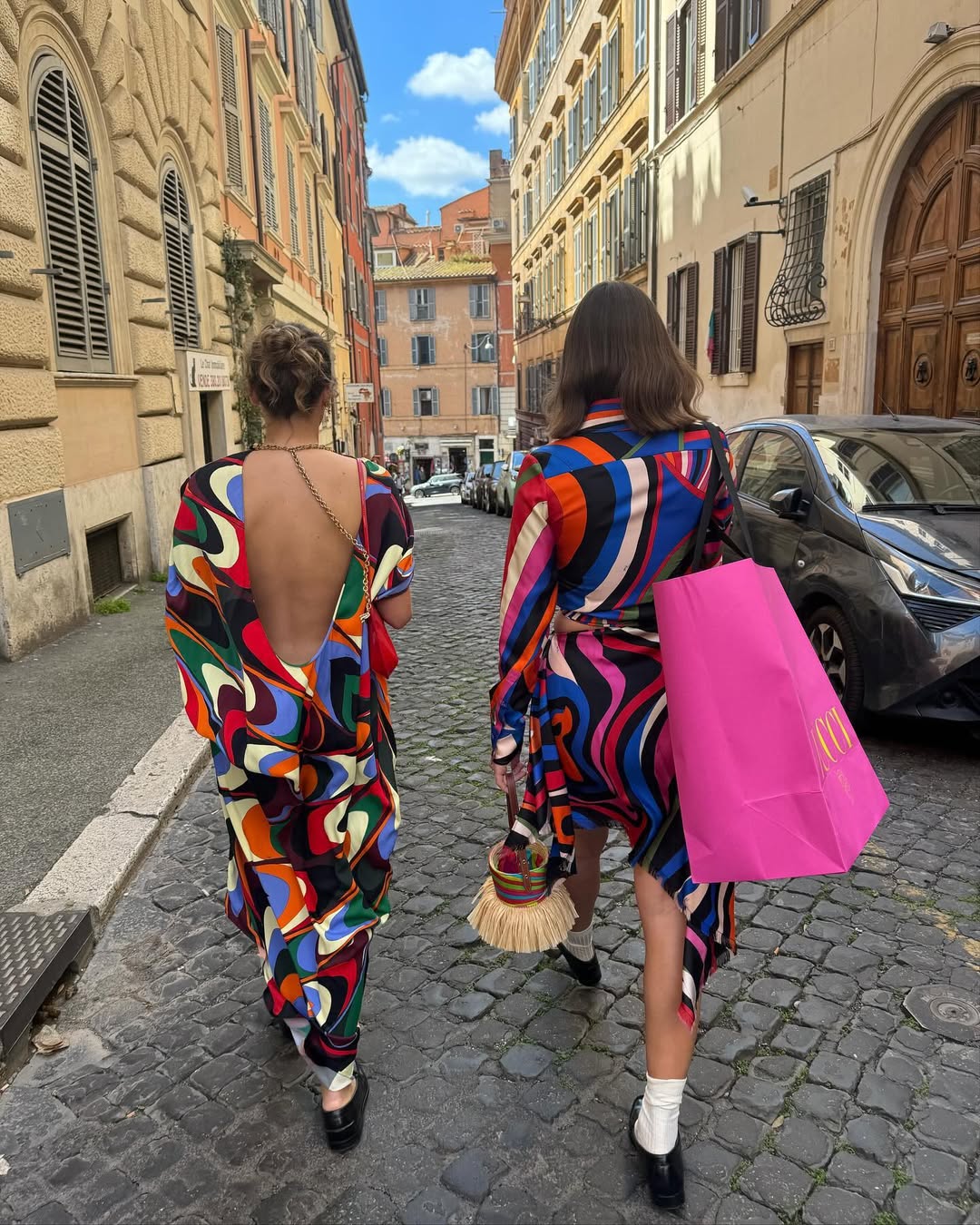 Two women in Pucci dresses, one carrying a pink Pucci shopping bag