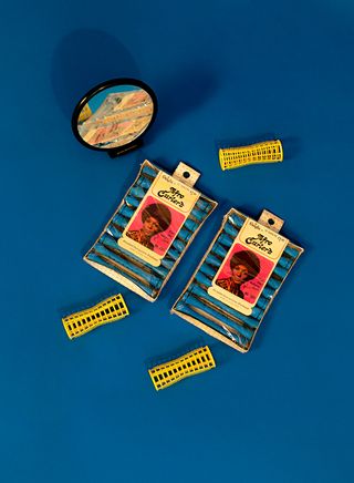 Two packs of afro curlers against a blue background