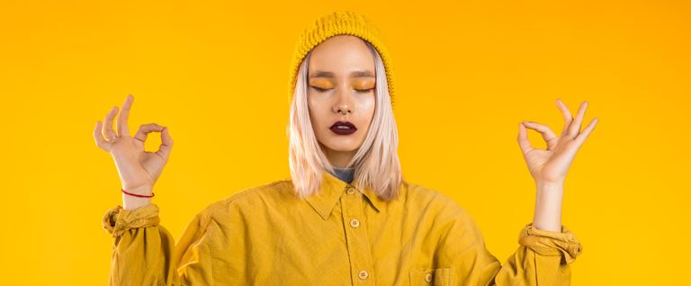 best meditation apps - woman With Eyes Closed Meditating Against Yellow Background