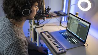 Man records music into a laptop wearing headphones