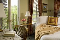 Bedroom with desk next to iron cast bed with open doorway and Venetian blinds. (Photo by: Jumping Rocks/Universal Images Group via Getty Images)