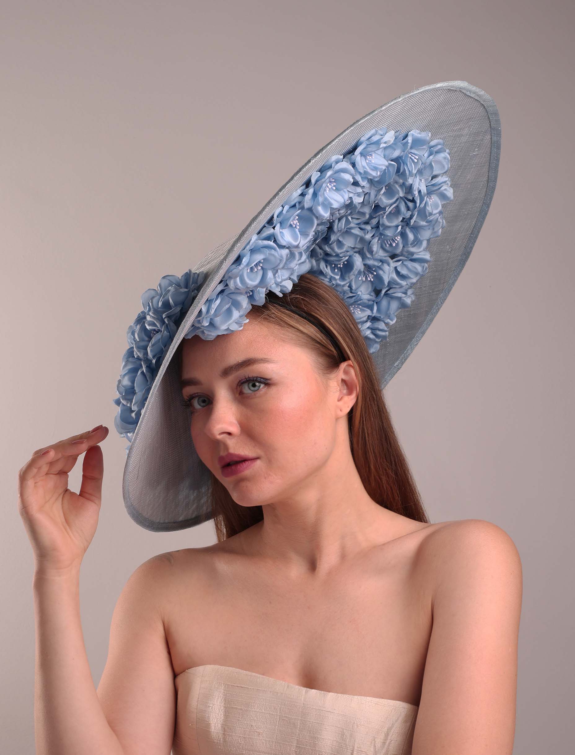 A woman wearing a large blue hat with flowers
