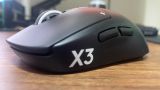 A Logitech G Pro X3 Superstrike gaming mouse on a wooden desk.