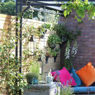 Metal rain pot in a garden with bright furniture and cushions in the background