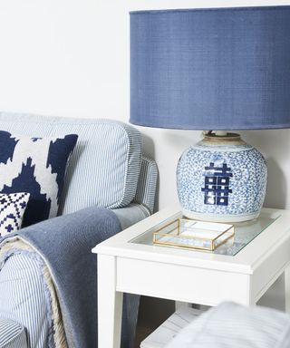 Blue table lamp on a white side table in a blue and white coastal living room
