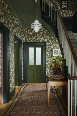 A large entryway with green and pink wallpaper and green painted ceilings