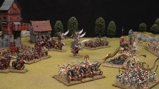 An army of Bretonnians and Tomb Kings clash on a fantasy battlefield with grassy fields, trees, and medieval buildings