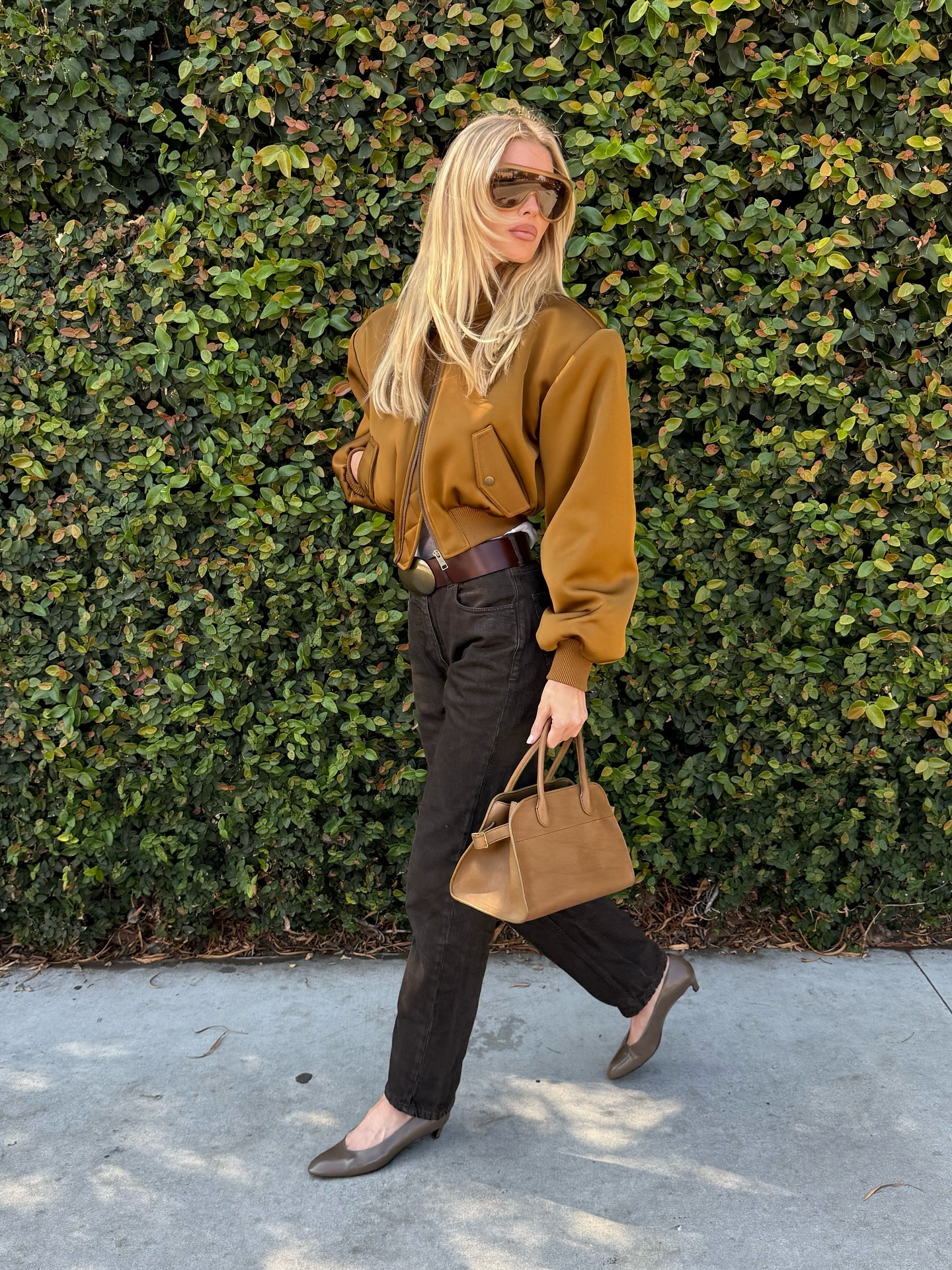 Elsa Hosk wearing a tan bomber jacket, brown jeans, and olive green shoes