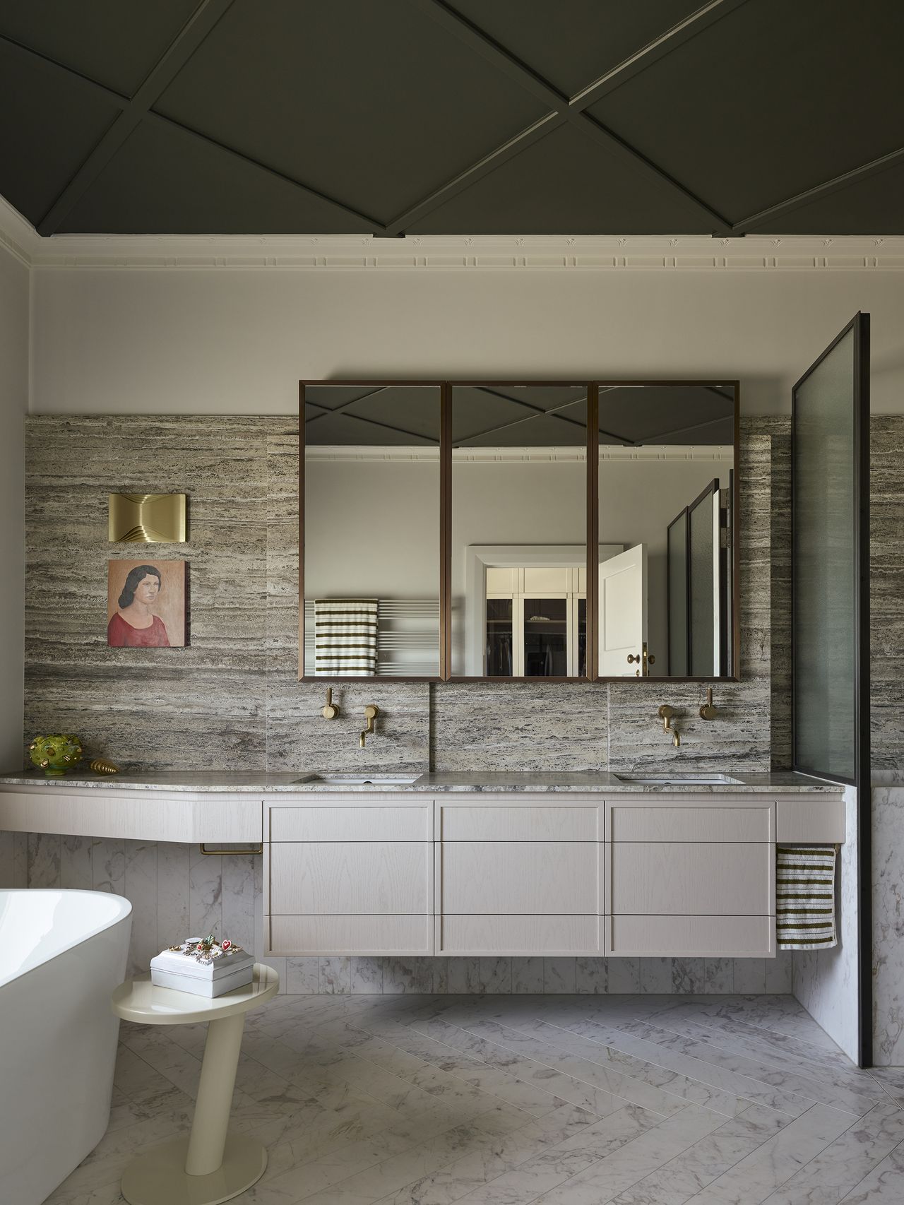modern bathroom with dark ceiling with decorative panels, gray floating cabinets, marble backsplash and marble flooring, freestanding bathtub and side table