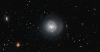 This galaxy is known as Mrk 820 and is classified as a lenticular galaxy. Surrounding Mrk 820 is a slew of other galaxy types from elliptical to spiral.