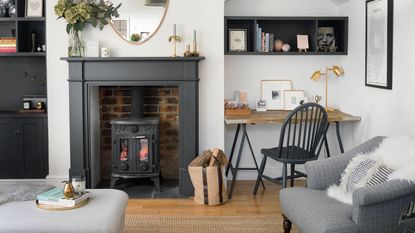 White living room with black fireplace and wood burner and a workspace in the curved alcove