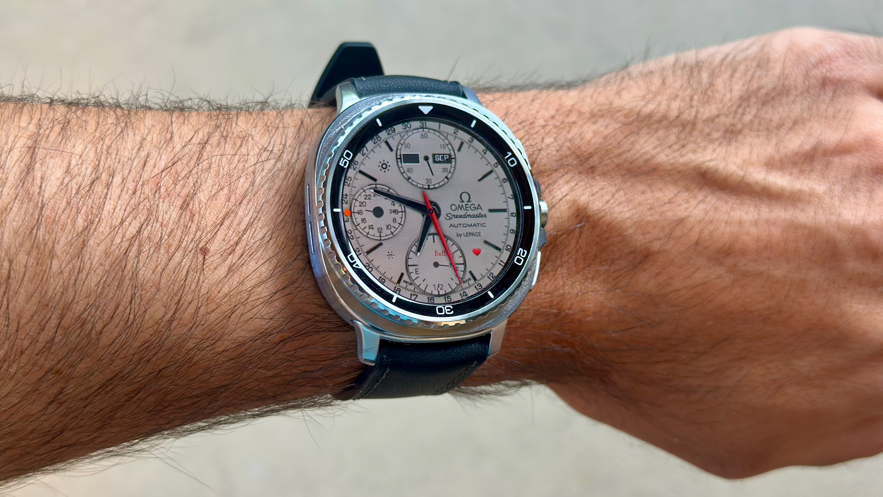 The Samsung Galaxy Watch 8 Classic on a person's wrist, showing a custom watch face from TIMEFLIK imitating an Omega luxury watch.