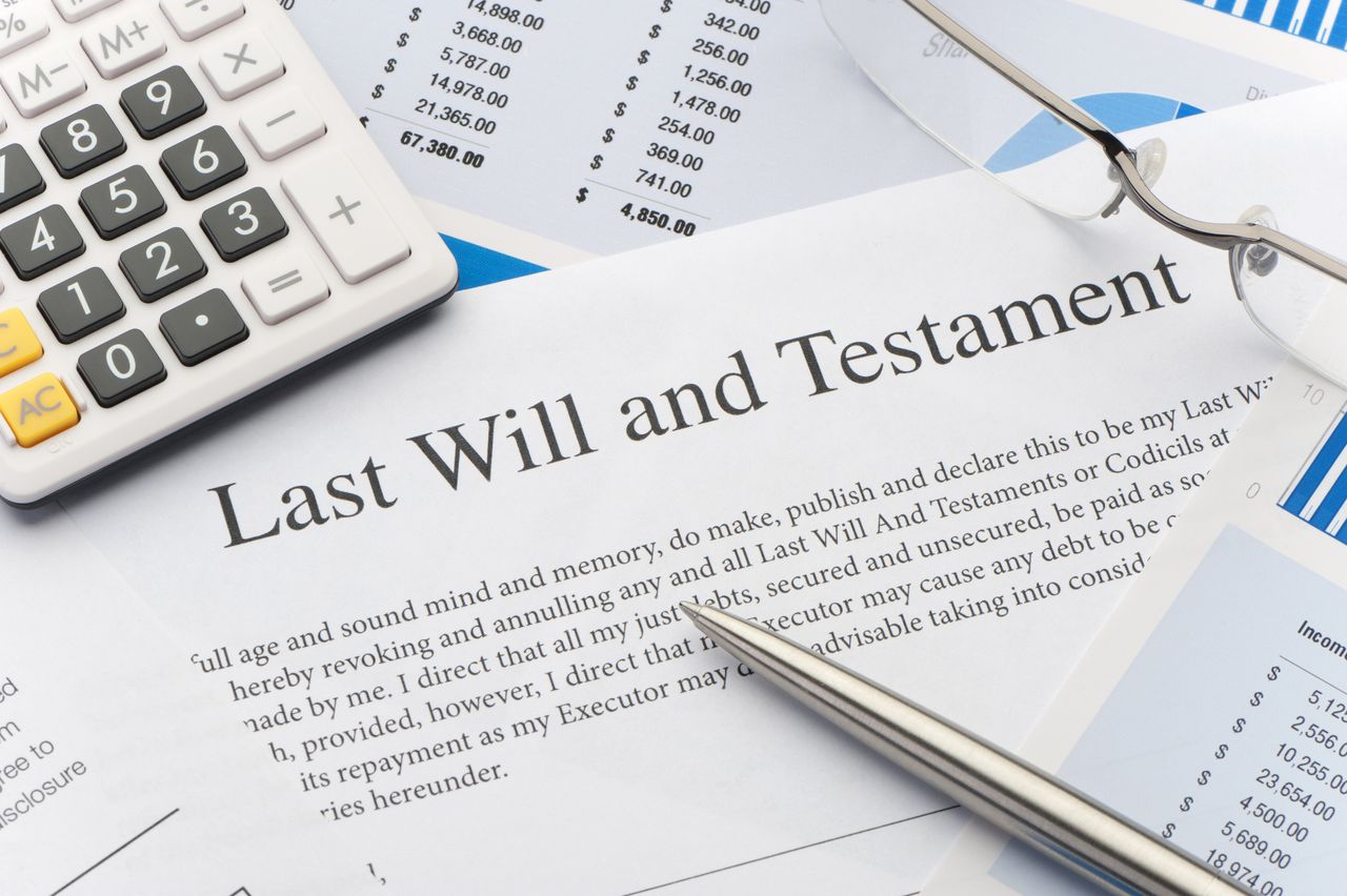 Close up of a last will and testament, calculator and other documents on a table.