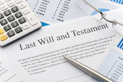 Close up of a last will and testament, calculator and other documents on a table.