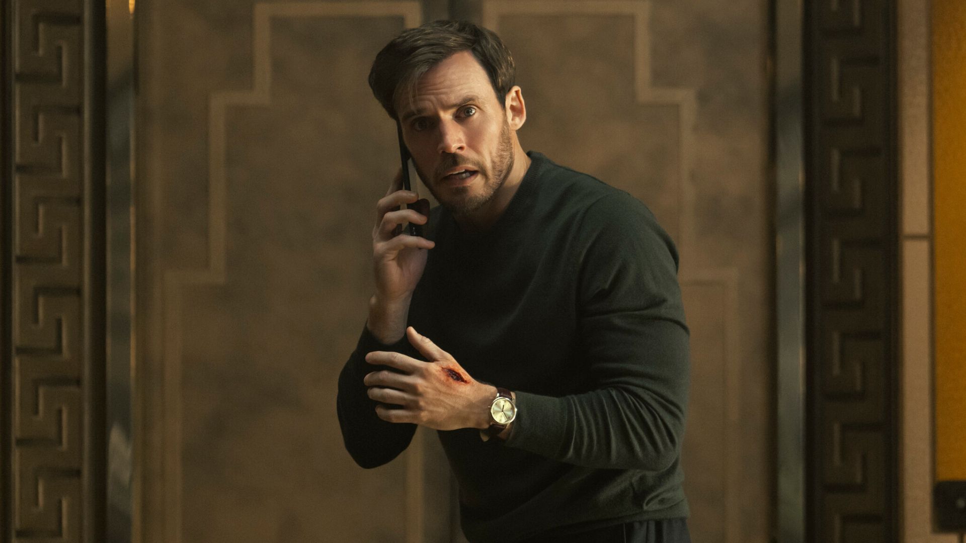 Sam Claflin holds a phone to his ear 