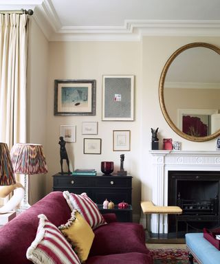 Living room with cream painted walls, fireplace, mirror and artwork on walls, purple sofa