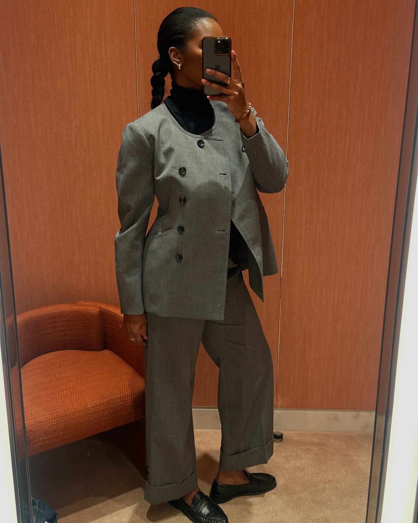 A woman wearing a stylish grey suit with a plait hairstyle