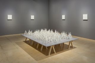White tube-like models sit on a low rise table inside a gallery