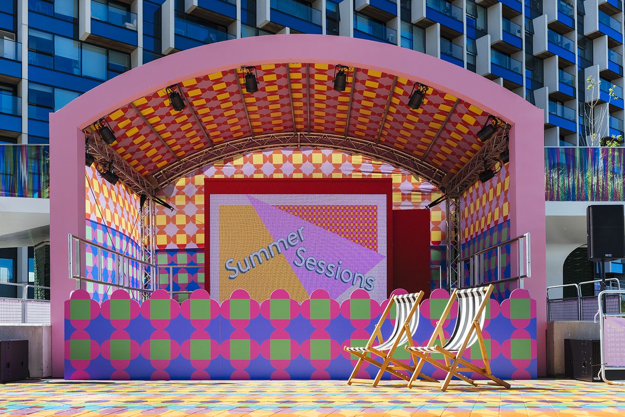 A colourful stage created by Yinka Ilori for Greenwich Peninsula, featuring a screen with the words &quot;Summer Sessions&quot;