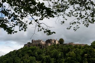 A view of Stirling Castle on top of a hill surrounded by trees, one of the family days out in Scotland for kids