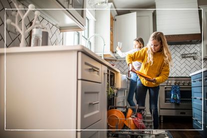 Two tween girls loading a dishwasher in their kitchen at home