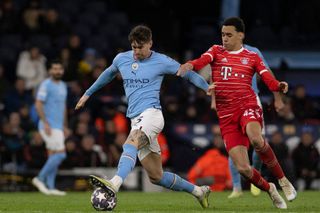 John Stones of Manchester CIty and Jamal Musiala of Bayern Munich battle for the ball during the UEFA Champions League quarterfinal first leg match between Manchester City and FC Bayern München at Etihad Stadium on April 11, 2023 in Manchester, United Kingdom.